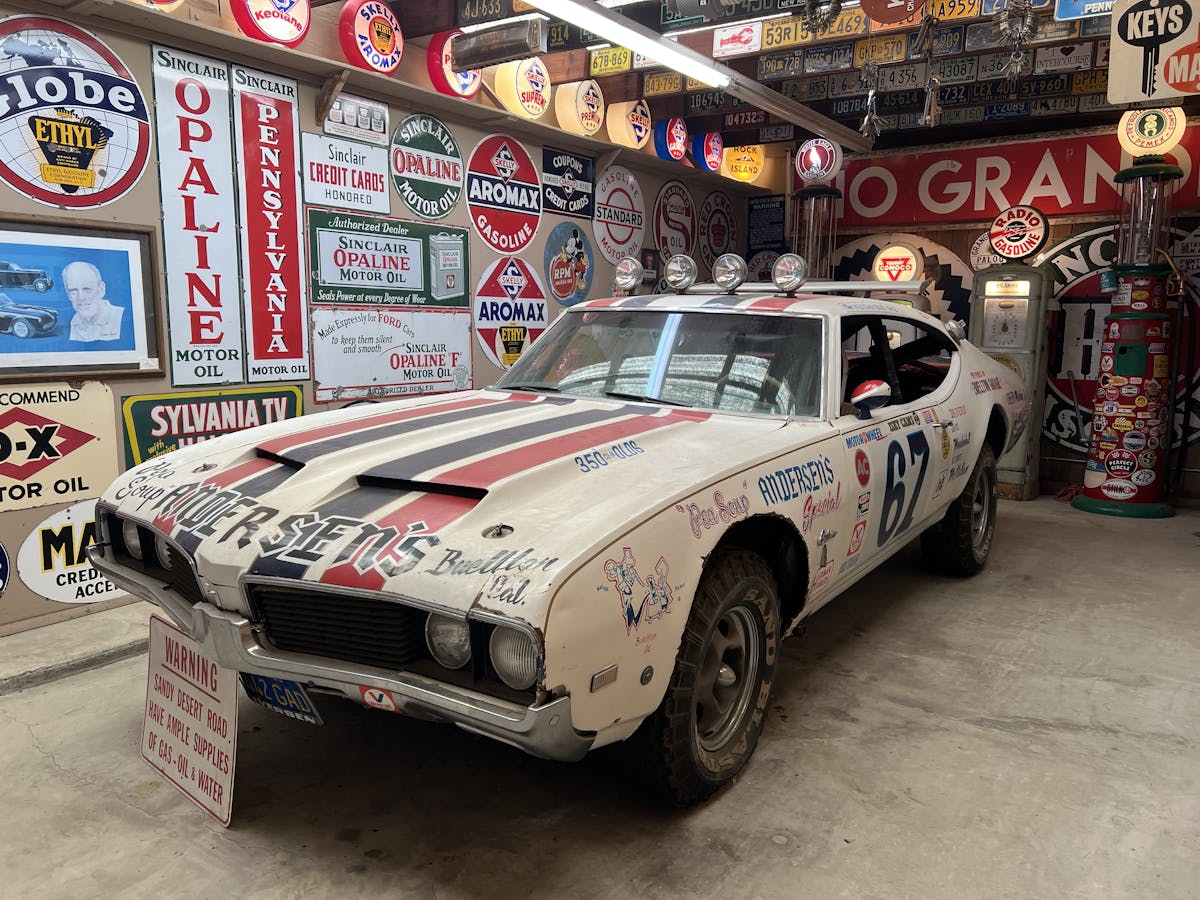 A very exciting classic racing car in a garage covered in more signs