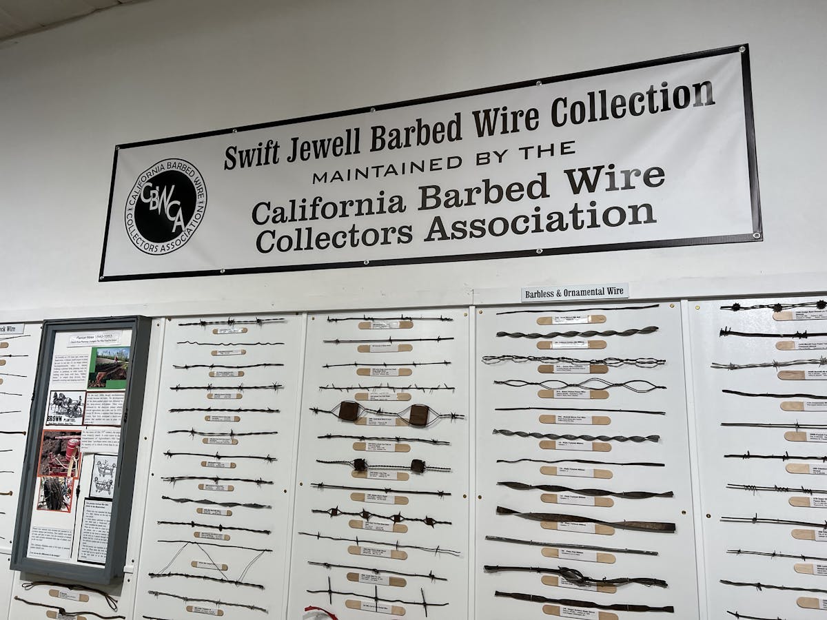 A sign says: Swift Jewell Barbed Wire Collection - above a wall full of barbed wire samples